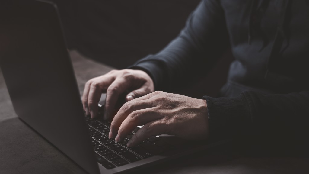 Hacker's hand pressing on the laptopic keyboard that begins a cyber attack